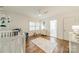 Well-lit bedroom with hardwood floors, a crib, area rug and a cozy armchair, creating a warm and inviting space at 601 Cherokee Rd, Charlotte, NC 28207