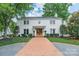 Charming two-story white brick home with mature trees, a brick driveway, and manicured landscaping at 601 Cherokee Rd, Charlotte, NC 28207