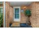 Close-up of the front door with a brick facade, a potted plant, and a welcome mat at 6577 Stoney Ridge Rd, Matthews, NC 28104