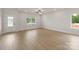 Open living room with light wood floors, white walls, a ceiling fan, and views of the backyard at 7225 Jerimoth Dr, Charlotte, NC 28215