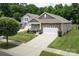 Beautiful home showcasing a stone facade, two-car garage, and lush green lawn at 7328 Strawberry Fields Ln, Charlotte, NC 28278