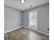 Comfortable bedroom with hardwood floors, a window providing natural light, and neutral gray walls at 8520 Mission Hills Rd, Charlotte, NC 28227