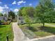 An elevated view of a charming single-story home with a long driveway, green lawn, and mature trees at 8520 Mission Hills Rd, Charlotte, NC 28227