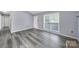 Bright living room featuring gray floors, a large window, and a white door at 8520 Mission Hills Rd, Charlotte, NC 28227