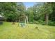 A lush backyard with mature trees featuring a classic swing set for outdoor enjoyment at 924 Carrington Dr, Charlotte, NC 28214