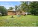 Expansive backyard featuring a charming brick home, swing set, and mature landscaping at 924 Carrington Dr, Charlotte, NC 28214