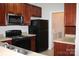 Efficient kitchen with wood cabinets, black appliances, and a laundry closet at 9823 Hyde Glen Ct, Charlotte, NC 28262