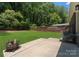 A backyard with a concrete patio, a green lawn, trees and wooden fence at 1027 Dresden W Dr, Charlotte, NC 28205