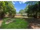A backyard with a green lawn and tall trees at 1027 Dresden W Dr, Charlotte, NC 28205