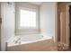 Bright bathroom showcasing a relaxing soaking tub with large grid window and glass-door shower at 11021 Travis Gulch Dr, Charlotte, NC 28277