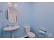 Charming powder room featuring a pedestal sink and a toilet at 11618 Macallano Dr, Charlotte, NC 28215