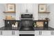 Close-up of the kitchen with modern appliances, white cabinets, and floating shelves showcasing decorative items at 1356 Briar Creek Rd, Charlotte, NC 28205