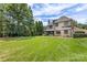 Lush backyard with expansive lawn, mature trees, and a view of the beautiful home exterior at 1728 Shadow Forest Dr, Matthews, NC 28105