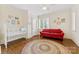 Bright bedroom featuring a crib, red sofa, and wood floors with circular accent rug at 1728 Shadow Forest Dr, Matthews, NC 28105