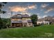 The rear of the house features an expansive lawn, outdoor sport court, neutral stucco siding, and metal roof accents at 1728 Shadow Forest Dr, Matthews, NC 28105
