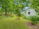 Large backyard featuring a well-manicured lawn, mature trees, storage shed, and a charming garden area at 206 Charlotte St, York, SC 29745