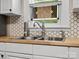 Close-up of the kitchen sink with a window, tile backsplash, and wood counters at 206 Charlotte St, York, SC 29745