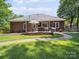Well-kept backyard featuring a brick house, patio area, and lush green lawn at 2616 Carmarthen Ct, Matthews, NC 28104