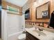 Traditional bathroom featuring a shower-tub combo, decorative wallpaper, and vanity storage at 2616 Carmarthen Ct, Matthews, NC 28104