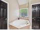 Cozy bathtub featuring black doors, a window, and neutral walls at 2616 Carmarthen Ct, Matthews, NC 28104