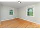 Bright bedroom featuring hardwood floors, two windows offering natural light, and neutral paint at 4014 Sulkirk Rd, Charlotte, NC 28210