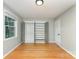 Minimalist bedroom featuring light grey walls, hardwood floors, and a built-in wardrobe with open doors at 4014 Sulkirk Rd, Charlotte, NC 28210
