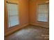 This is a small bedroom with carpet and two windows with blinds at 407 W Mill St, Landis, NC 28088