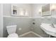 Vintage gray bathroom with a white toilet, sink, mirror, and gray tiled walls at 5742 Murrayhill Rd, Charlotte, NC 28210