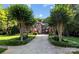 Stunning exterior view of a stone and brick home featuring a long driveway lined with mature trees and manicured landscaping at 617 Beauhaven Ln, Waxhaw, NC 28173
