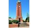 Tall brick clock tower with a stepped brick entrance surrounded by landscaping at 7007 Creft Cir, Indian Trail, NC 28079