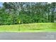 View of the tree-covered, sloped land from the road with a yield sign at 11201 Johnson Davis Rd, Huntersville, NC 28078