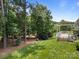 Lush green backyard with mature trees, pergola covered deck, and well-manicured lawn at 11329 Fullerton Place Nw Dr, Huntersville, NC 28078
