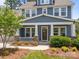 Charming front porch of blue home with white columns and railings, adorned with a wreath and rocking chairs at 11329 Fullerton Place Nw Dr, Huntersville, NC 28078