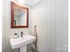 Charming powder room featuring a pedestal sink, decorative mirror, and wainscoting at 1207 E 36Th St, Charlotte, NC 28205