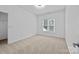 Bright bedroom with neutral carpet, white walls, and a window providing natural light at 15400 Groveland St, Huntersville, NC 28078