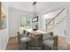 Staged dining room featuring a dining table with seating, a modern light fixture, and access to the staircase at 15400 Groveland St, Huntersville, NC 28078