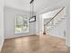 Bright empty dining room featuring hardwood floors, a modern light fixture, and access to the staircase at 15400 Groveland St, Huntersville, NC 28078