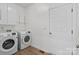 Well-lit laundry room with modern washer and dryer units and white cabinets at 15400 Groveland St, Huntersville, NC 28078