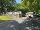 Well-maintained RV with wooden deck, a shed, and a picnic table on a lot with gravel and grassy areas at 155 Indian Harbor Trl # E243, Mount Gilead, NC 27306