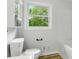 Bright bathroom featuring a toilet, vanity, and a window view of a lush green tree at 1837 6Th Nw Ave, Hickory, NC 28601