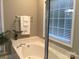 Bright bathroom features a large soaking tub and window with white blinds at 1842 Caroline Way, Fort Mill, SC 29715