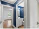 Bathroom with blue walls, white cabinets and sink, next to a room with light wood floors at 202 Glenn Ave, Kannapolis, NC 28081