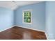 A blue bedroom features hardwood floors and a window overlooking the yard at 202 Glenn Ave, Kannapolis, NC 28081