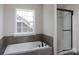 Modern bathroom features a soaking tub with gray tiled surround and a sleek glass-enclosed shower at 236 Paradise Dr, Belmont, NC 28012