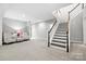 Spacious living room with neutral carpet, staircase, and two armchairs with a side table and lamp at 2501 Christenbury Hall Nw Ct, Concord, NC 28027