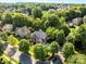 Aerial of a brick home nestled among mature trees in a residential neighborhood at 2504 Fallbrook Pl, Concord, NC 28027