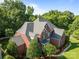 Aerial view of a beautiful two-story brick home with lush landscaping and a gray roof at 2504 Fallbrook Pl, Concord, NC 28027