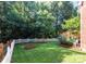 Private backyard featuring a white picket fence, mature trees, and a well-maintained lawn at 2504 Fallbrook Pl, Concord, NC 28027