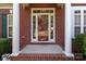 Elegant brick home entrance featuring a glass front door with white columns and green shutters at 2504 Fallbrook Pl, Concord, NC 28027