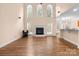 Open-concept living room with a fireplace, hardwood floors, and large windows allowing natural light at 2504 Fallbrook Pl, Concord, NC 28027